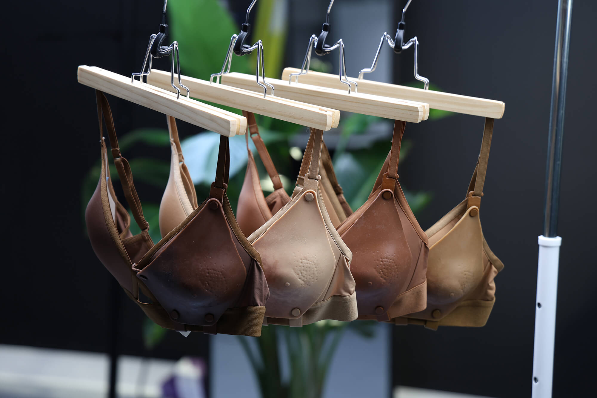 Four bras in varying shades of brown hanging on a rail.