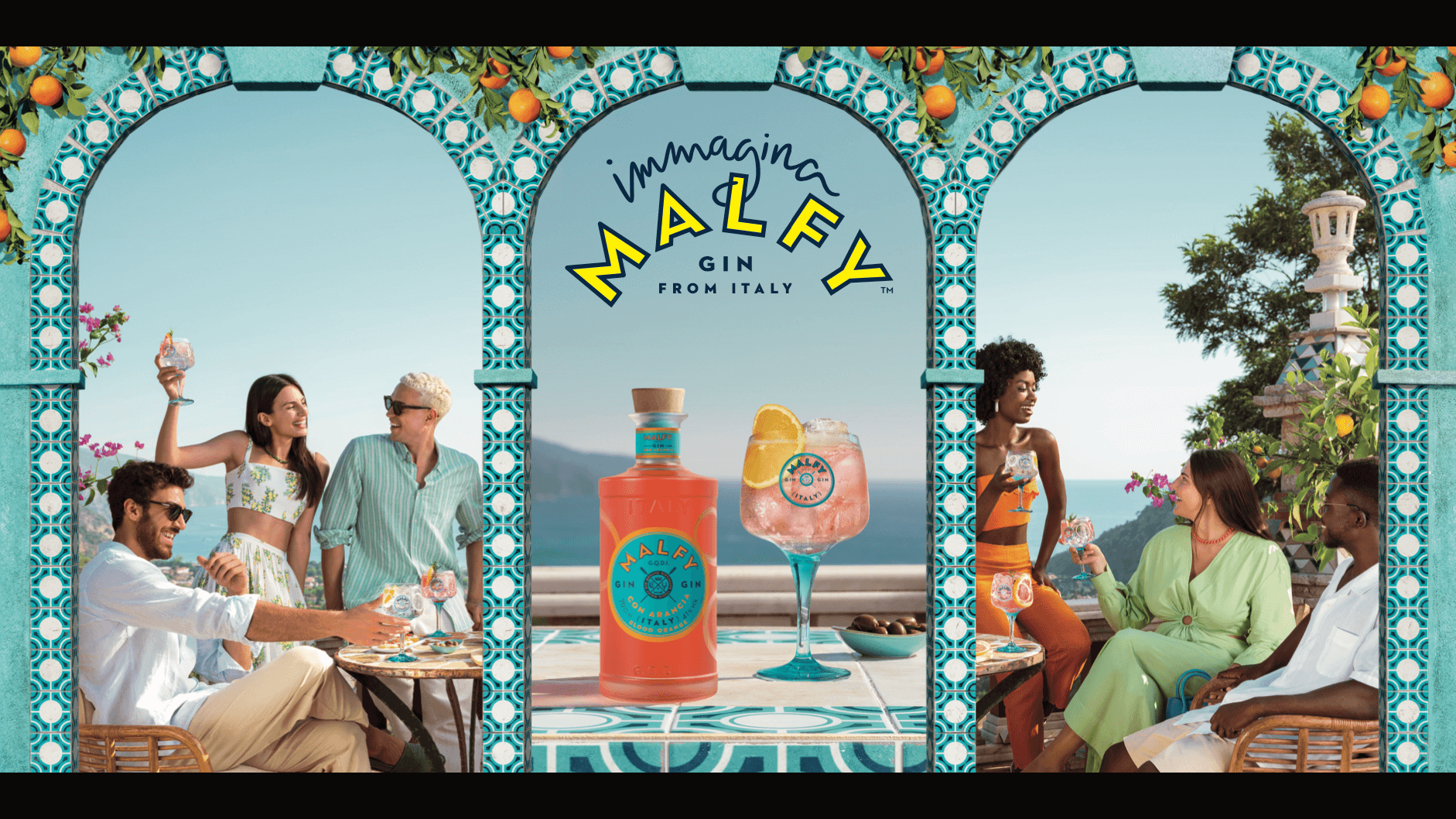 A Malfy Gin bottle and drink sit on display between 3 Mediterranean arches. 6 young people in summer clothes chat and laugh, enjoying the season.