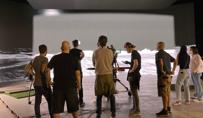 A team of casually dressed individuals are seen from behind a film set.