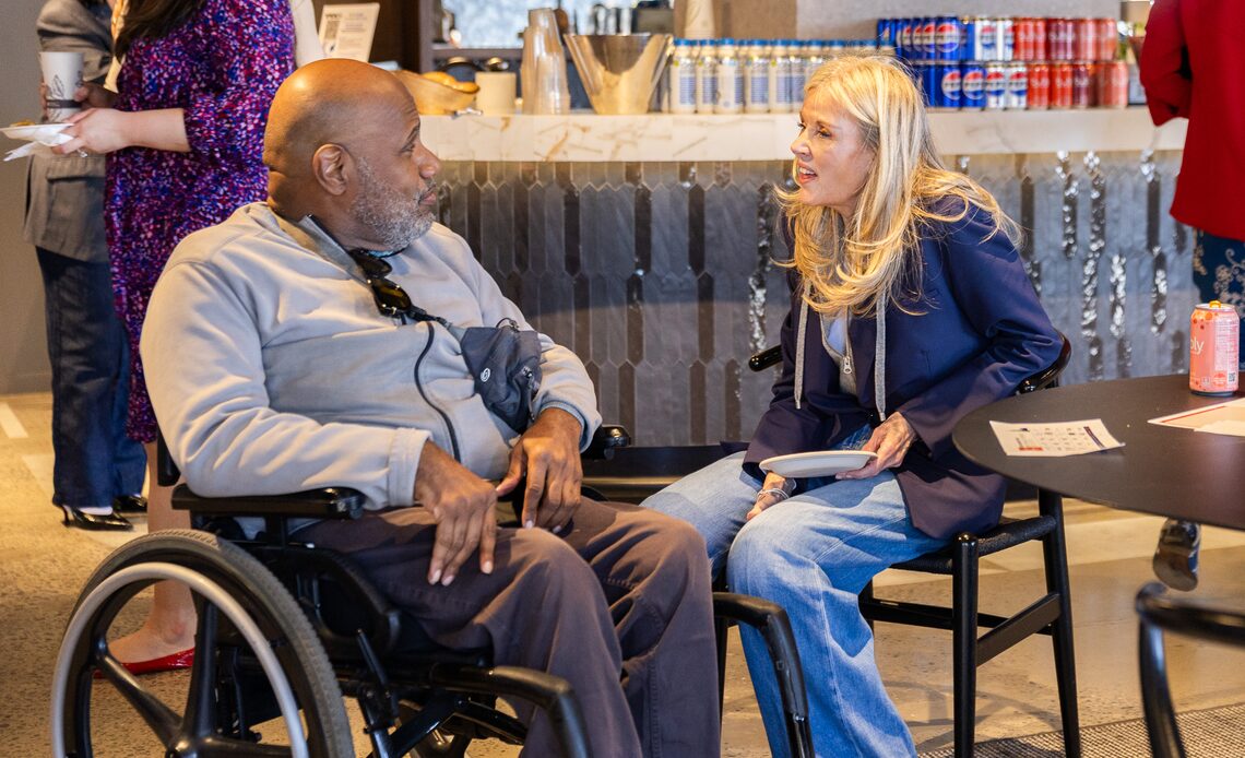 Two Omnicom colleagues, one using a wheelchair, talking in a workplace lounge